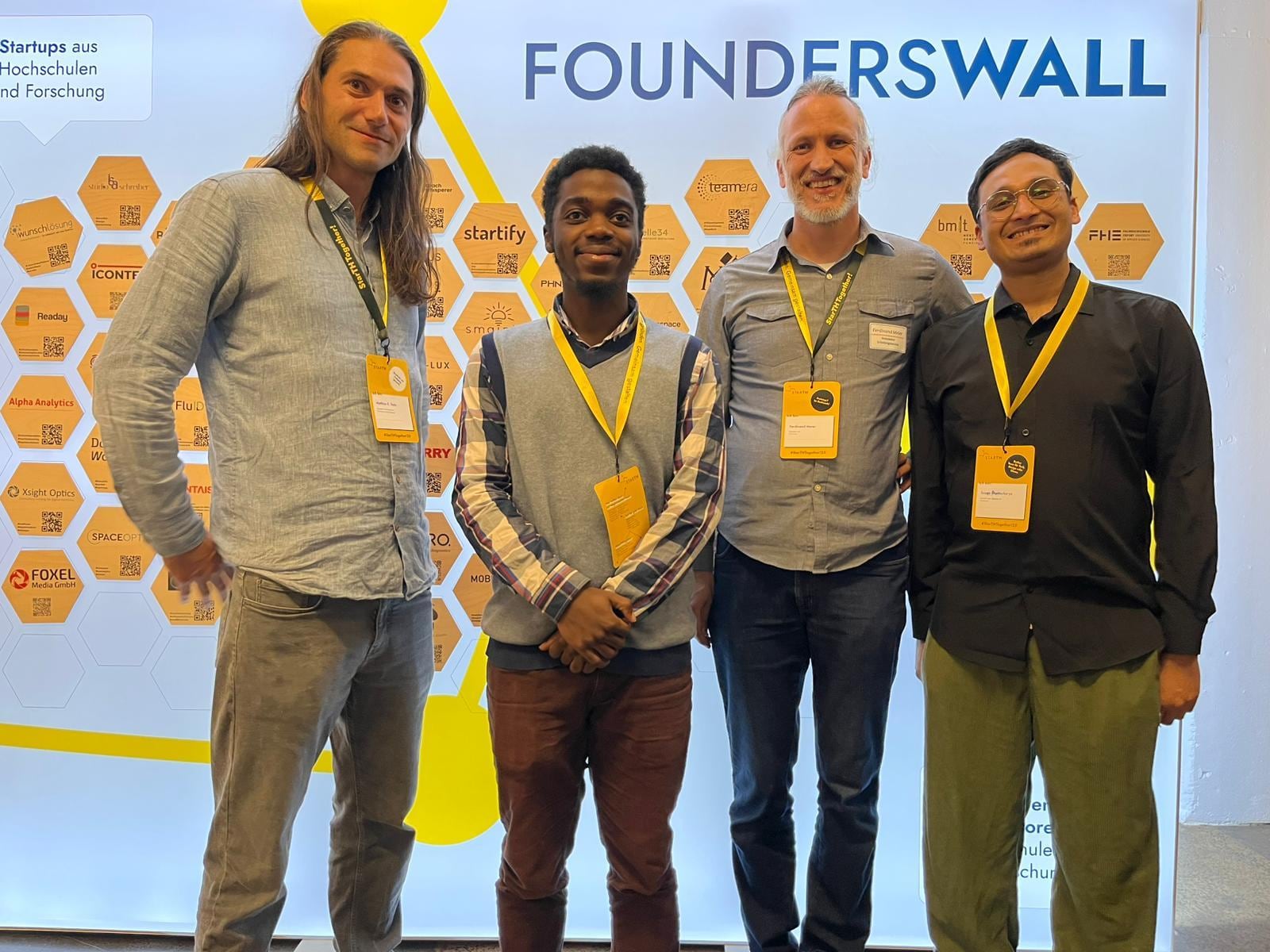Group photo with founders in front of the FoundersWall at a startup event
